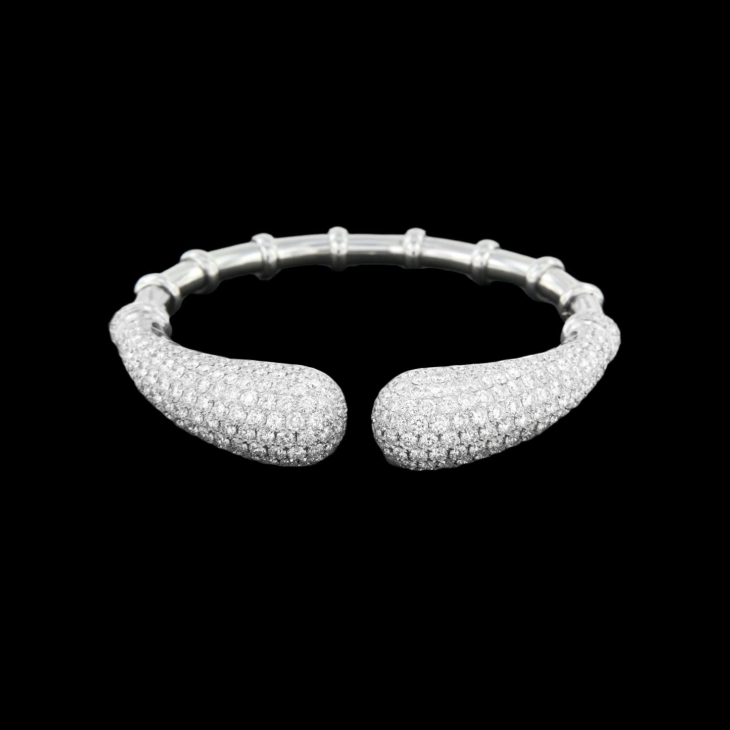 An 18K white gold open cuff bracelet featuring 14.51 carats of pavé-set round natural diamonds on curved, tapered ends, complemented by a segmented polished band.
