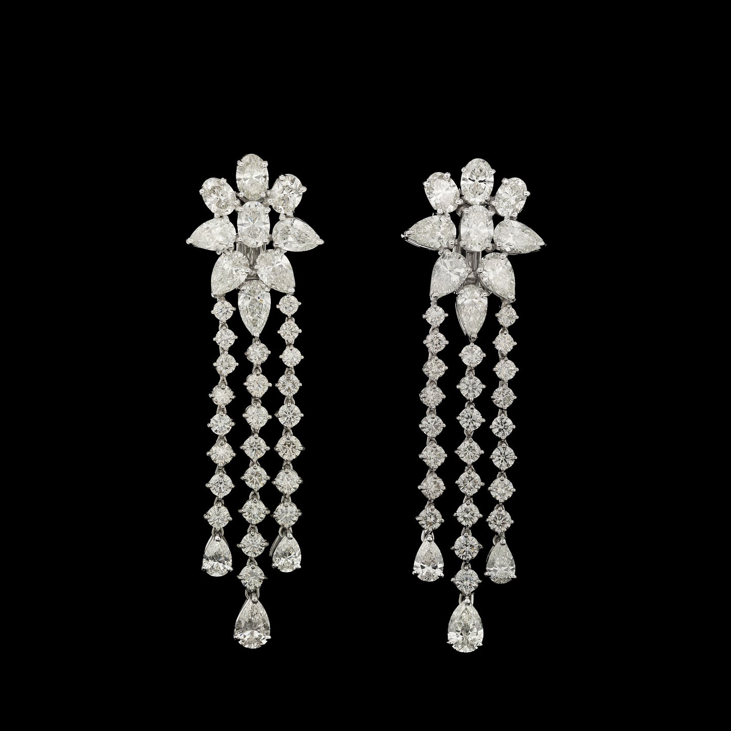 18K White Gold earrings featuring 6.62ct Round Brilliant, 9.80ct Pear Shape, and 4.54ct Oval Diamonds in a cascading three-row design.