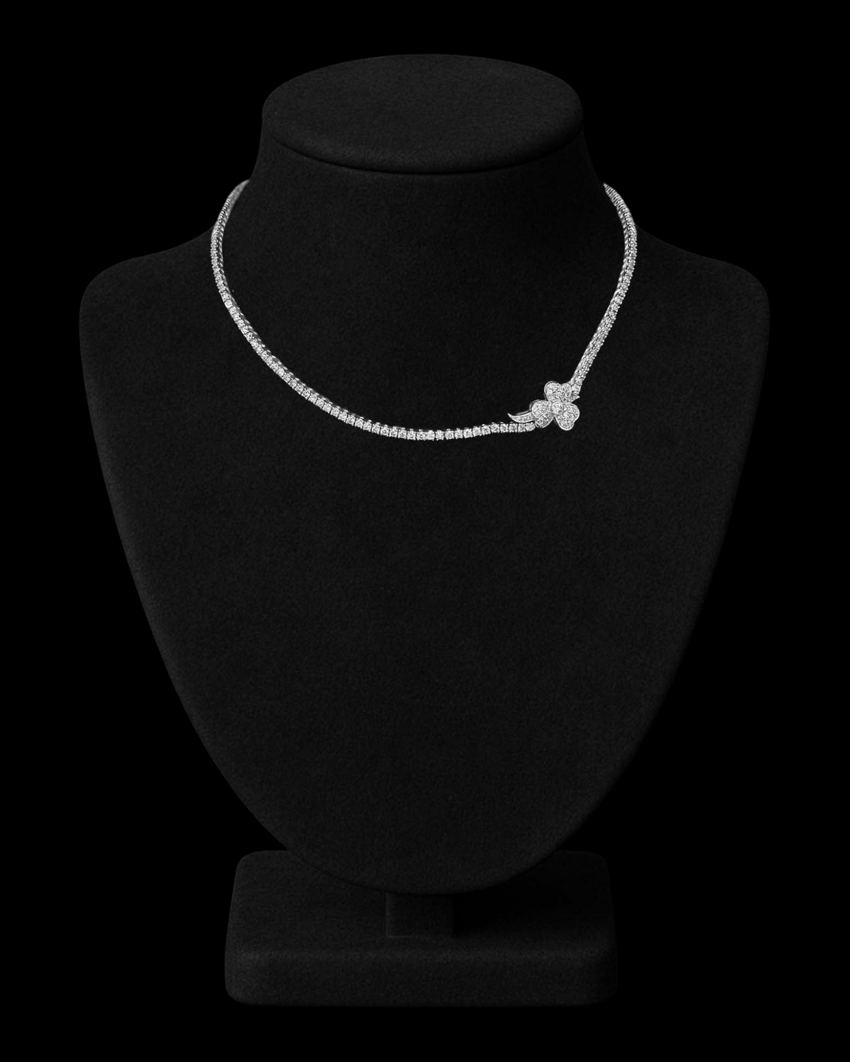 hofjewellery Clover Petals 18k white gold tennis necklace with a floral diamond cluster on a black display bust.