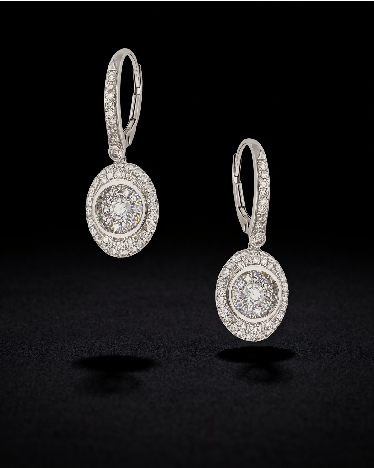 Oval illusion-set diamond drop earrings with diamond halos and hooks in 18K white gold, reference 1951E.